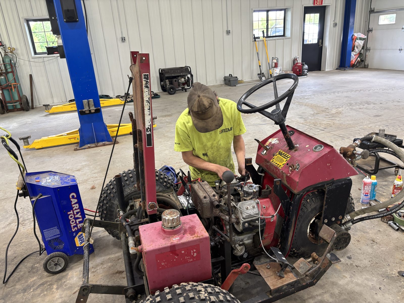 A student repairing a hydraulic utility vehicle in a contractor's shop