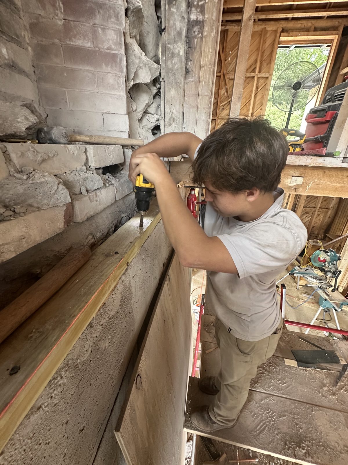 A Tupper Lake student driving screws into wall framing